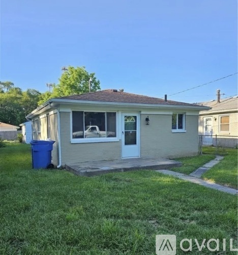 A small house with a blue trash bin in front.