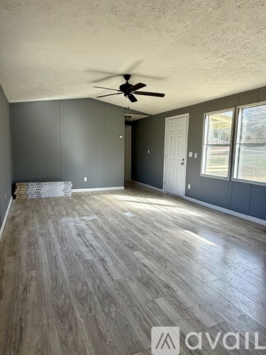 A room with a ceiling fan and wood flooring.
