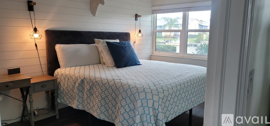 A bedroom with a bed, nightstand, and window.