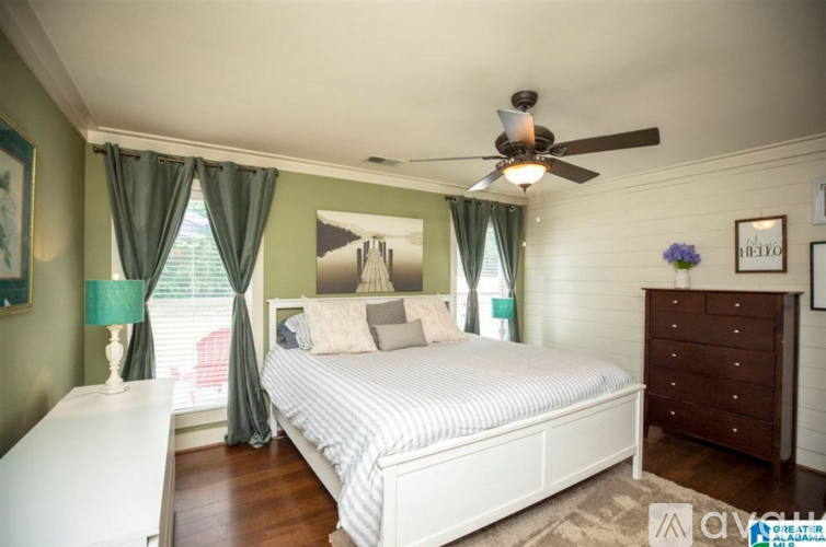 A bedroom with a bed, dresser, and window with curtains.