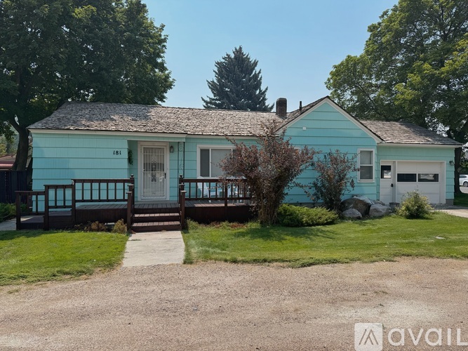 A blue house with a porch and a tree in front.