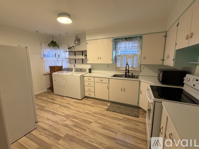 A kitchen with white appliances and wooden floors.