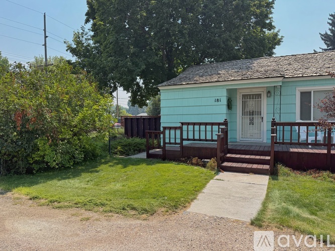 A blue house with a porch and a green lawn.
