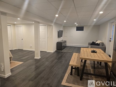 A room with a wooden table and bench, a television, and a couch.