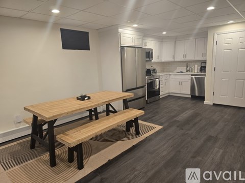 A kitchen with a table and chairs in the foreground and a refrigerator, microwave, and oven in the background.