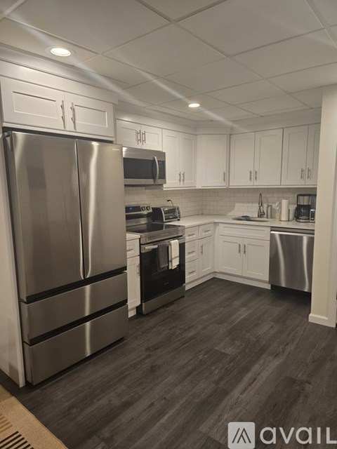 A modern kitchen with a stainless steel refrigerator and wooden flooring.