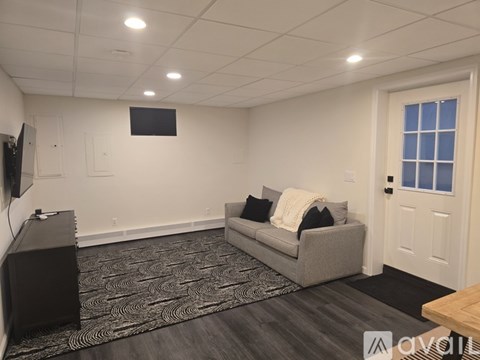 A living room with a grey couch and a black speaker.