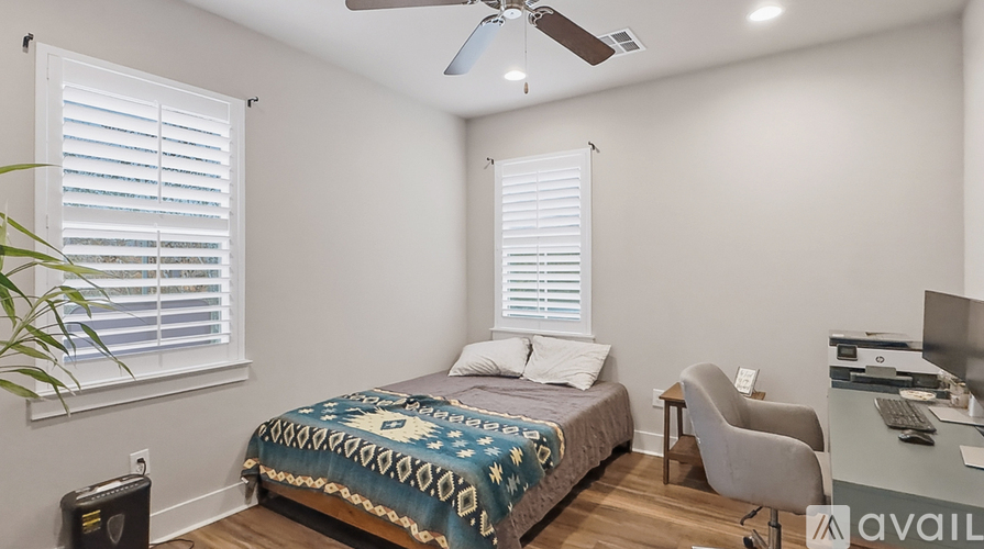 A bedroom with a bed, chair, and a ceiling fan.