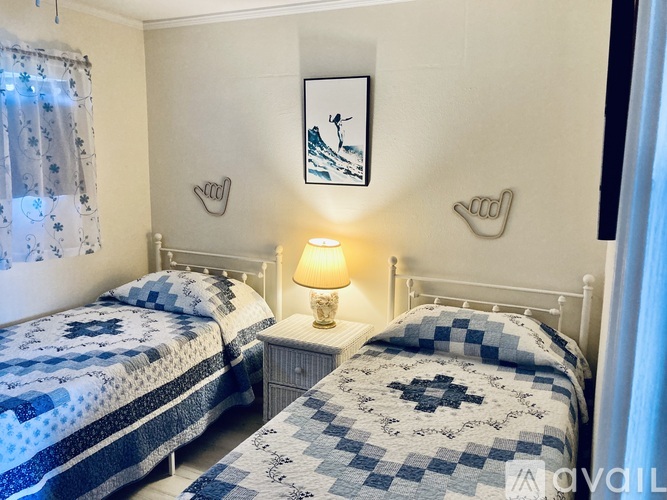 A bedroom with two beds and a nightstand with a lamp.