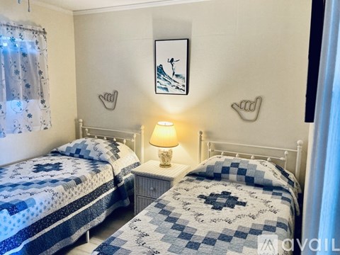 A bedroom with two beds and a nightstand with a lamp.