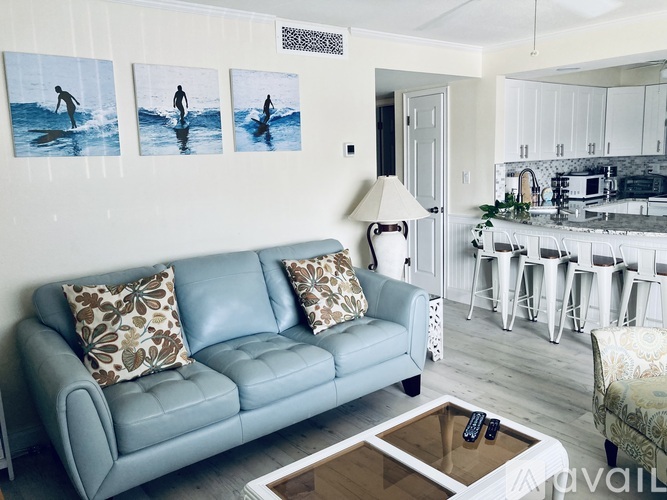 A living room with a blue couch and pictures of a person surfing on the wall.