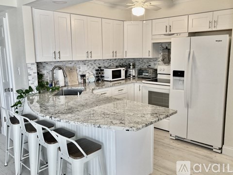 A kitchen with white cabinets and a marble countertop.