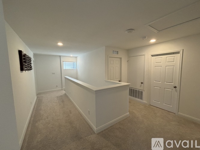 A spacious room with a carpeted floor and white walls.