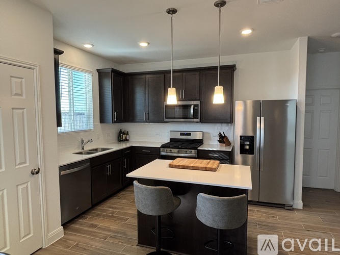A kitchen with a white island and dark wood cabinets.