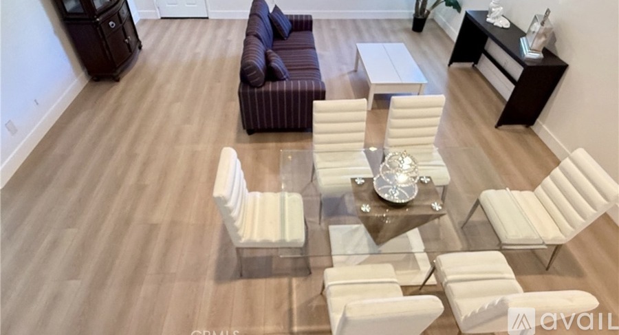A living room with a glass table and white chairs.
