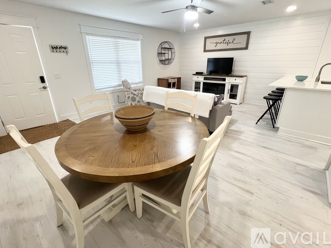 A dining room with a wooden table and white chairs.