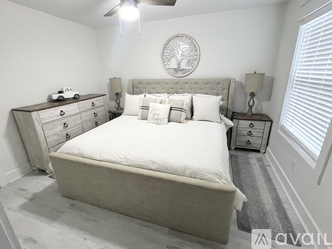 A bedroom with a large bed, a dresser, and a nightstand with a lamp.