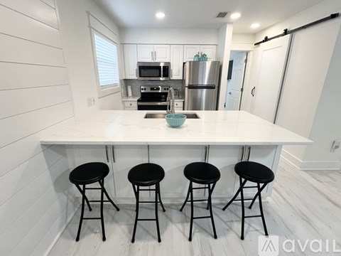 A kitchen with white cabinets and a white island with black stools.