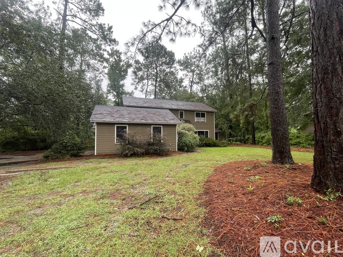 A house with a grey roof is surrounded by trees and grass.