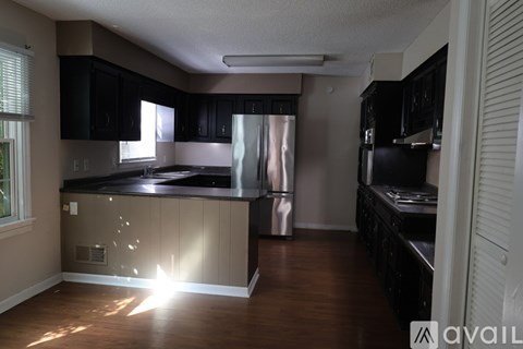 A kitchen with black cabinets and a stainless steel refrigerator.