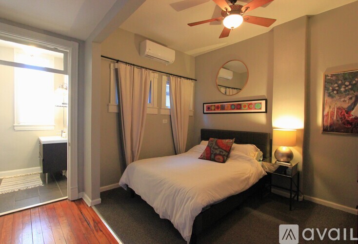 A bedroom with a bed, a ceiling fan, and a window with curtains.