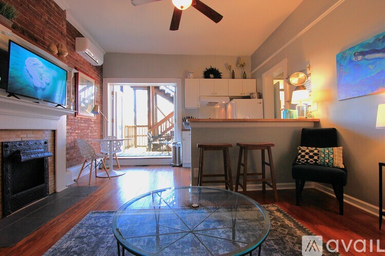 A living room with a glass table and a television on the wall.