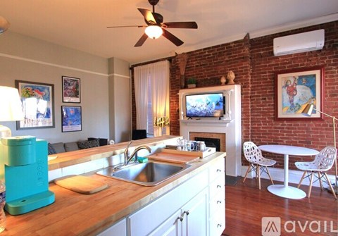 A kitchen with a wooden counter top and a brick wall.