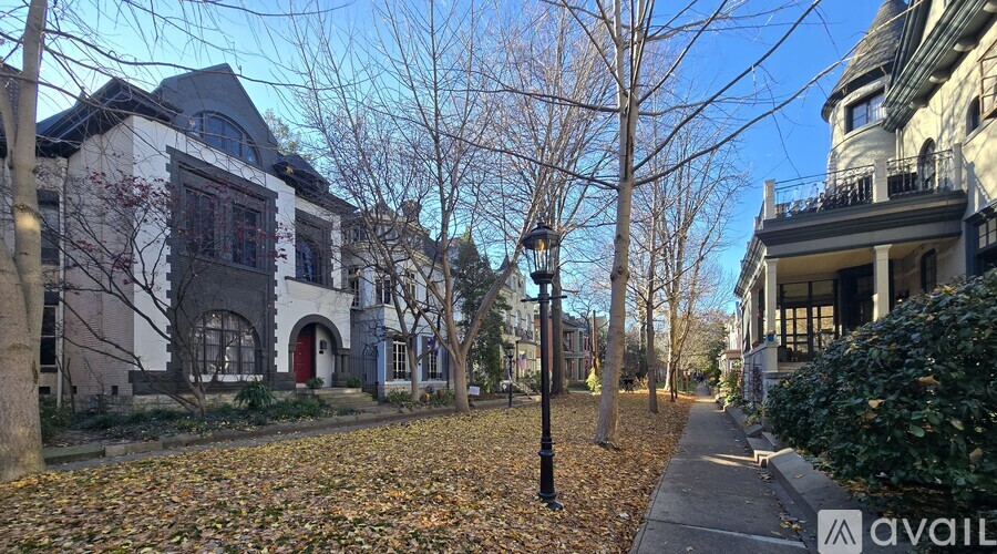 A street with a sidewalk, trees, and buildings.