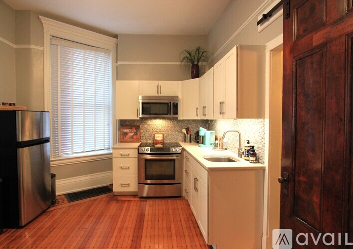 A kitchen with white cabinets and a wooden floor.