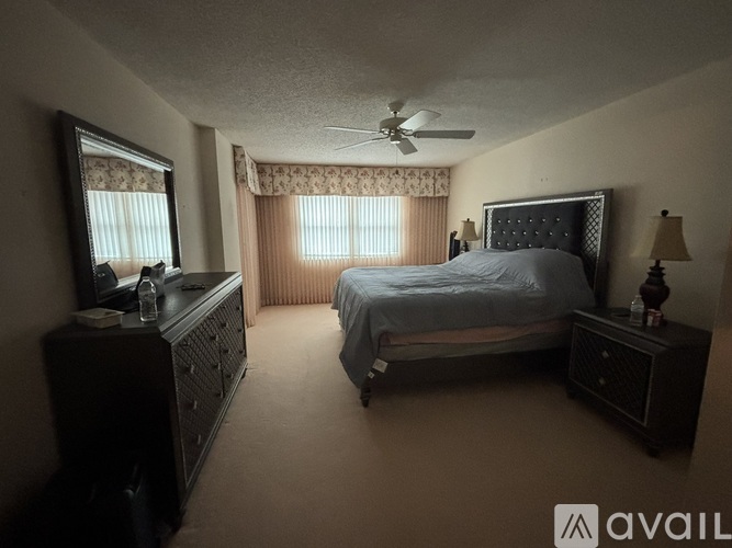 A bedroom with a bed, dresser, and window with curtains.
