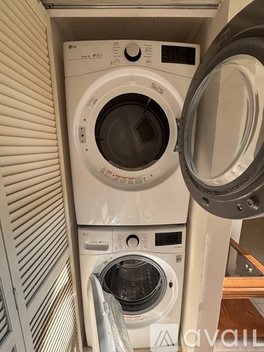 A white washing machine with the door open is in a small space.