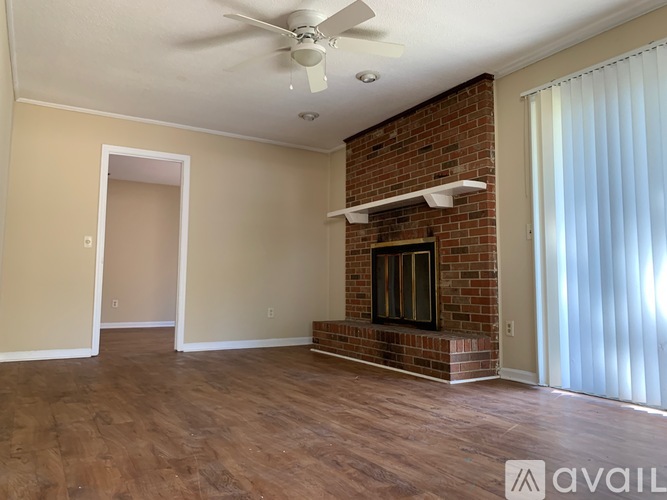 A living room with a fireplace and a ceiling fan.