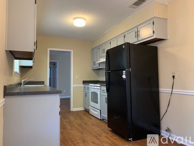 A kitchen with a black fridge and white cabinets.