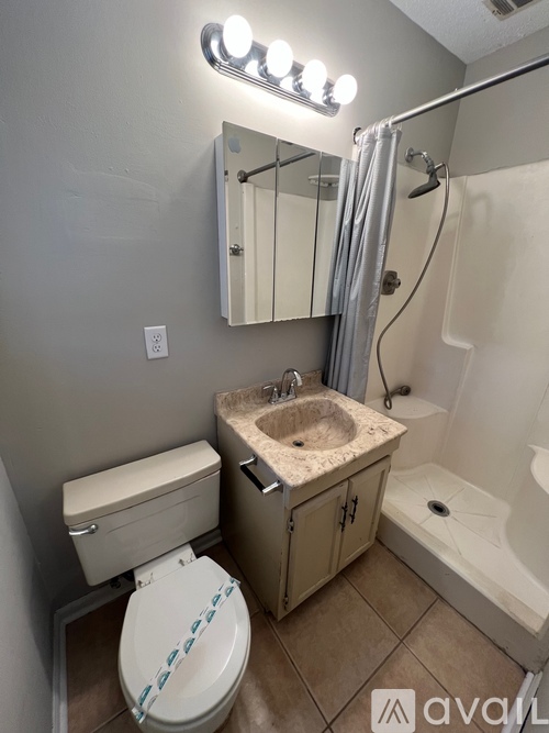 A bathroom with a toilet, sink, and mirror.
