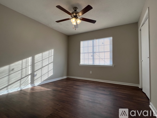 A room with a ceiling fan and a window letting in sunlight.