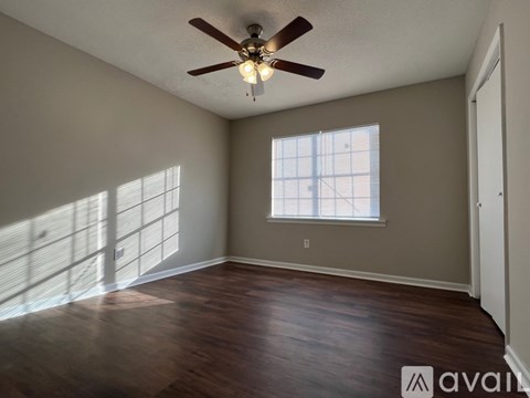 A room with a ceiling fan and a window letting in sunlight.