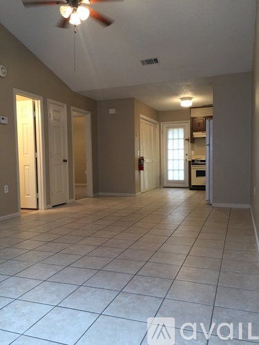 A spacious room with tile flooring and a ceiling fan.