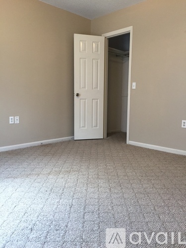 A room with a white door and carpeted floor.