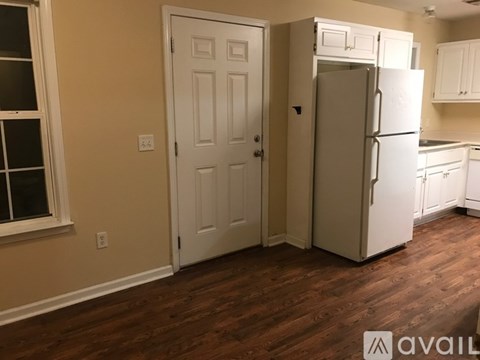 A kitchen with a white refrigerator and wooden floors.