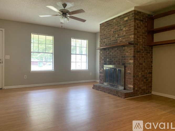 A living room with a fireplace and a ceiling fan.