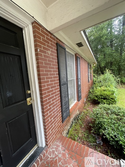A black door is on the left and a brick wall is on the right.