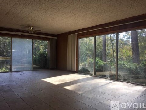 A room with tiled floors and sliding glass doors leading to a wooded area.