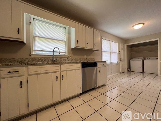 A kitchen with white cabinets and a tiled floor.