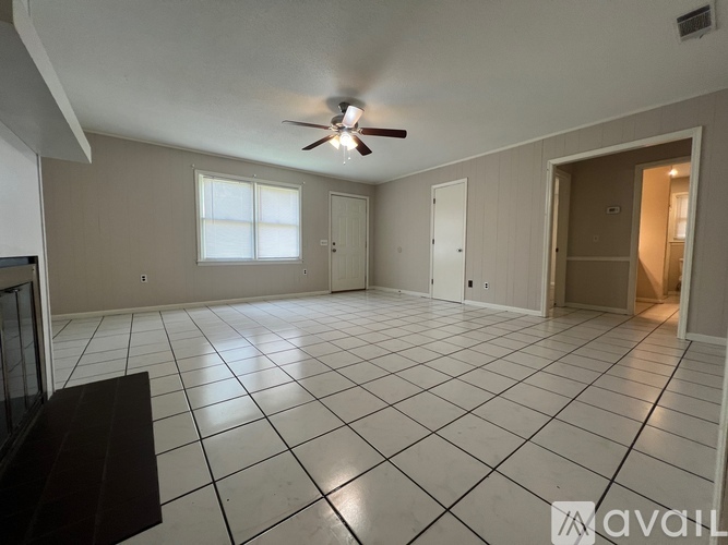 A spacious room with a ceiling fan and tiled flooring.