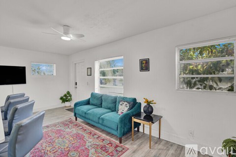 A living room with a blue couch and a rug.