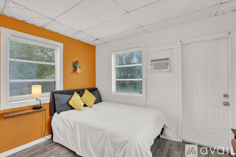 A bedroom with a white bed and a window with blinds.