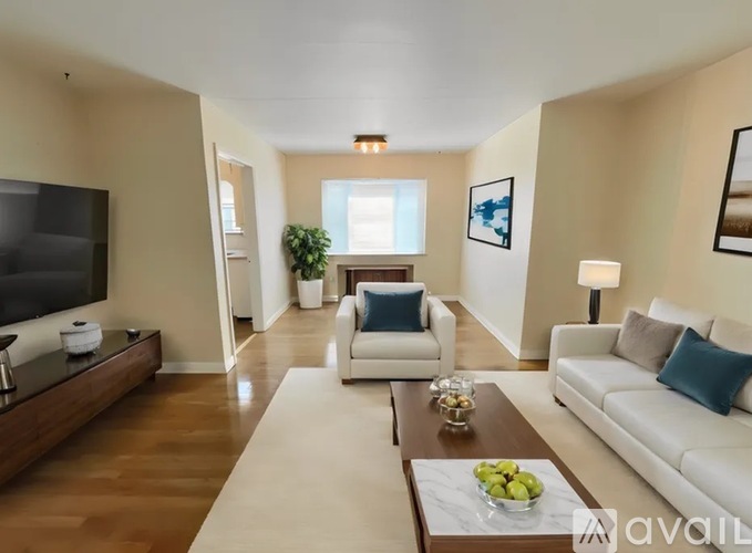 A living room with a white couch, a coffee table, and a flat-screen TV.
