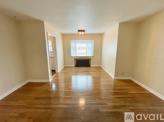A spacious room with wooden flooring and a window.