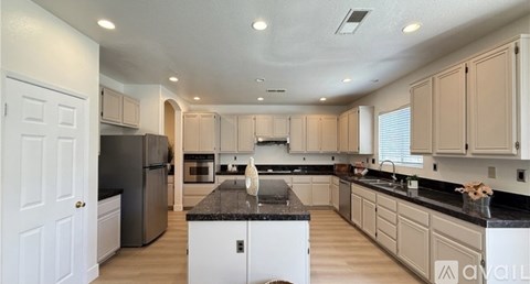 A kitchen with white cabinets and a black countertop.