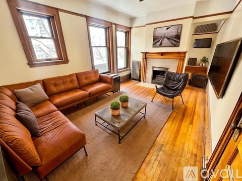 A living room with a brown leather couch and a fireplace.